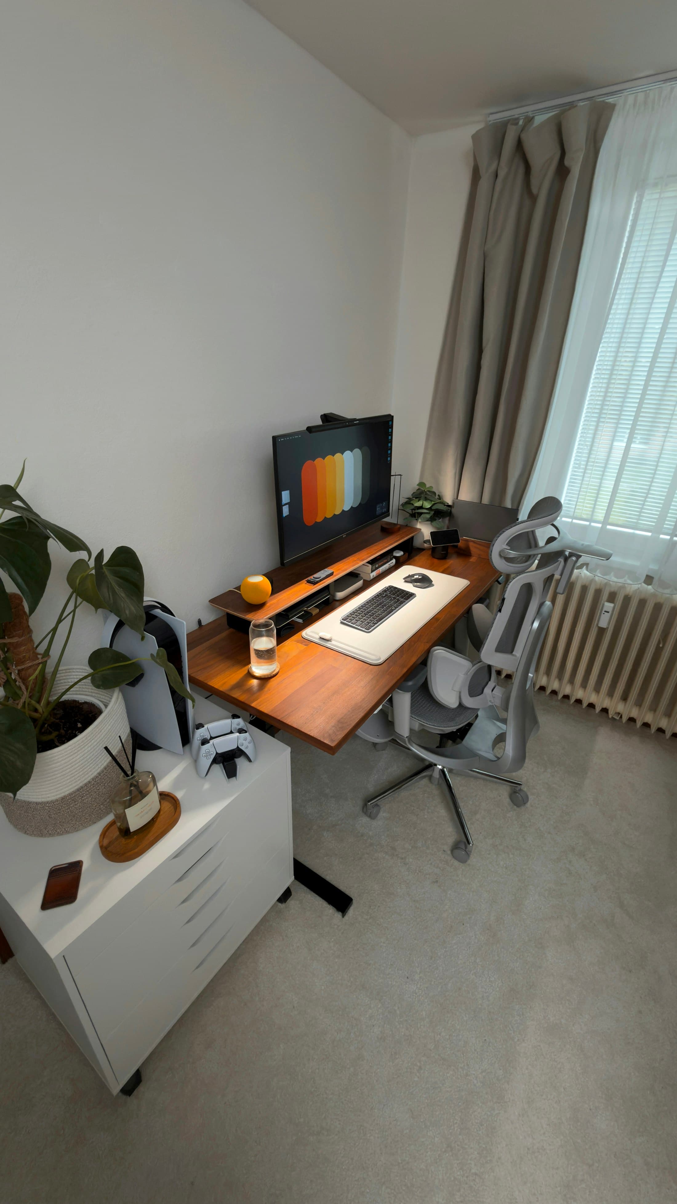 A compact home workspace with a wood desk, plant, screen shelf, and edited desktop objects.