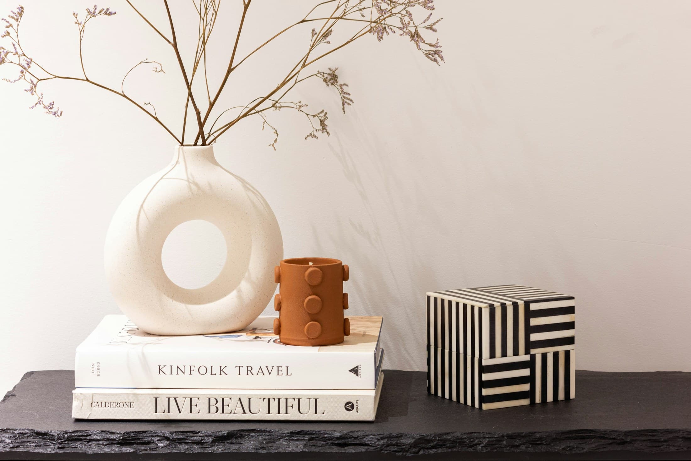 A styled shelf with books, a sculptural vessel, a small ceramic accent, and open negative space.